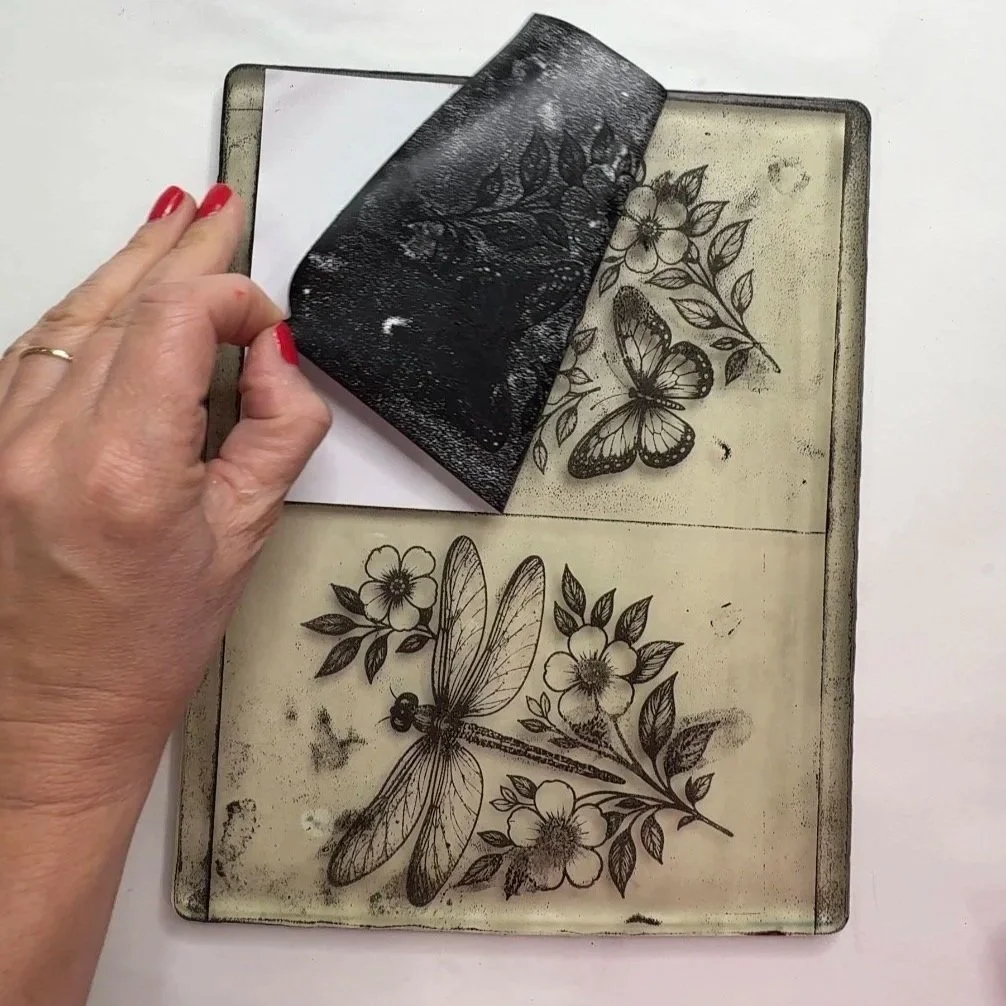 Peeling back paper to reveal a black butterfly and flower image transferred from a gelli plate