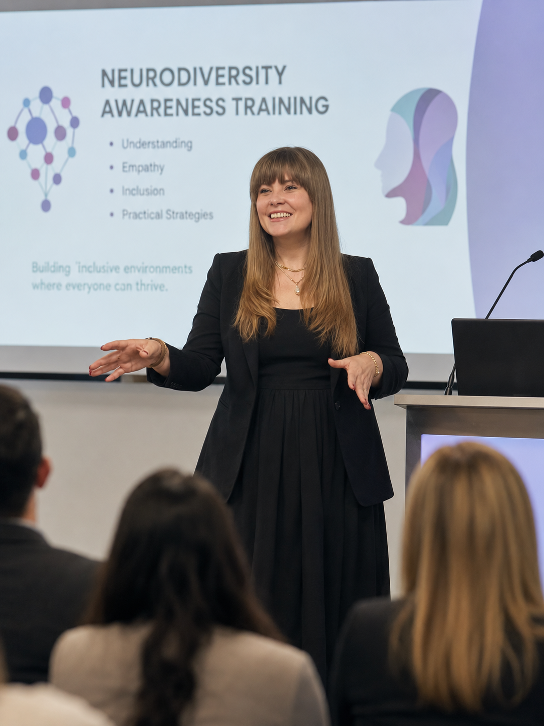 A woman giving a presentation on neurodiversity awareness training to an audience in a conference room.
