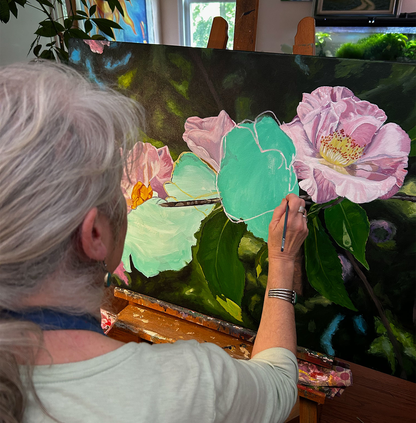 Art Jean Campbell sits before her easel and works on the camellia painting she hopes to include in the Magic City Art Connection festival. The painting shows several completed camellias with big blank melon green areas for the camellias to come.