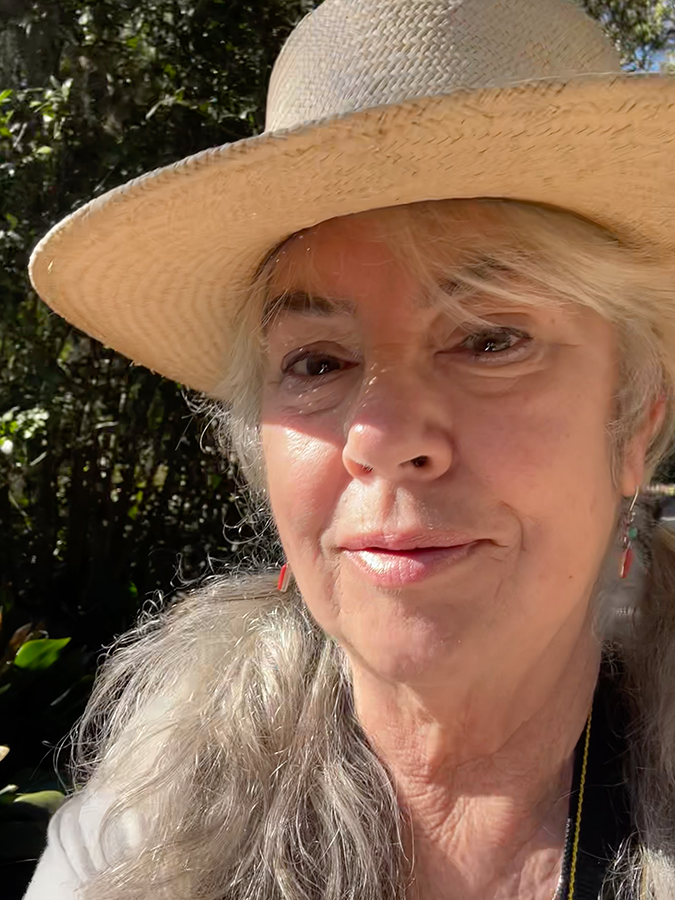 Photo of artist Jean Campbell in a straw hat in the bright sun.