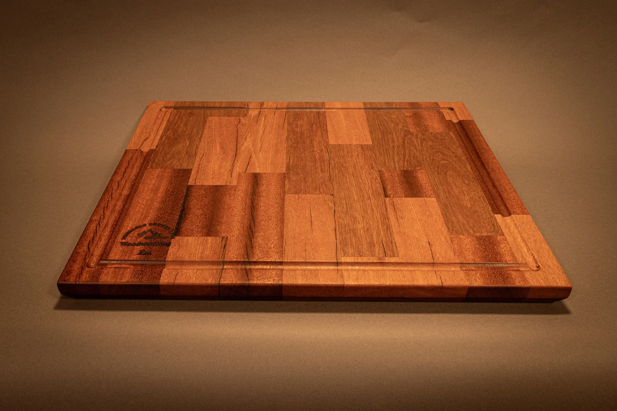 A rectangular wooden cutting board with a natural wood finish on a dark surface.