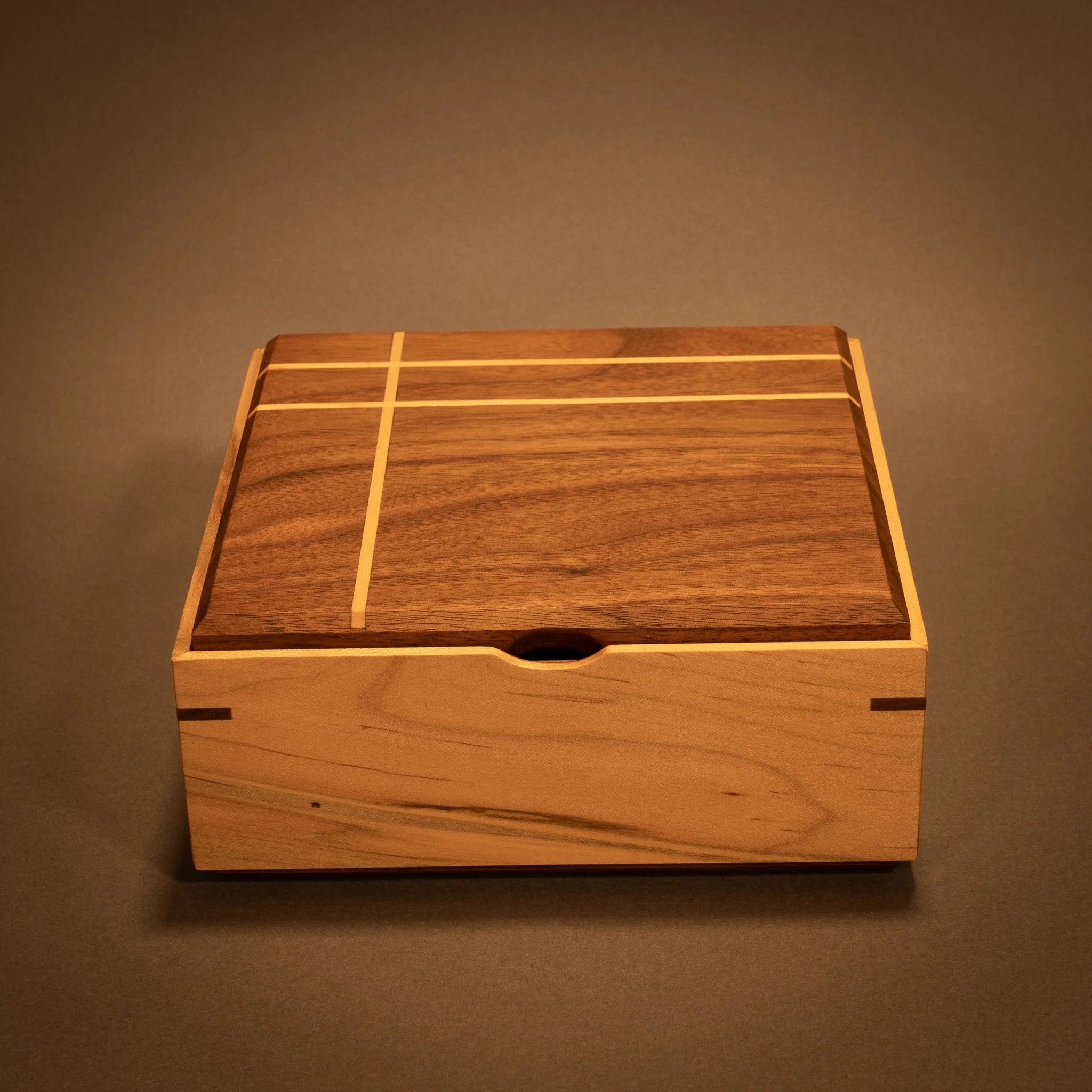 Wooden drawer with divided compartments on a dark surface, with a plain dark brown background.