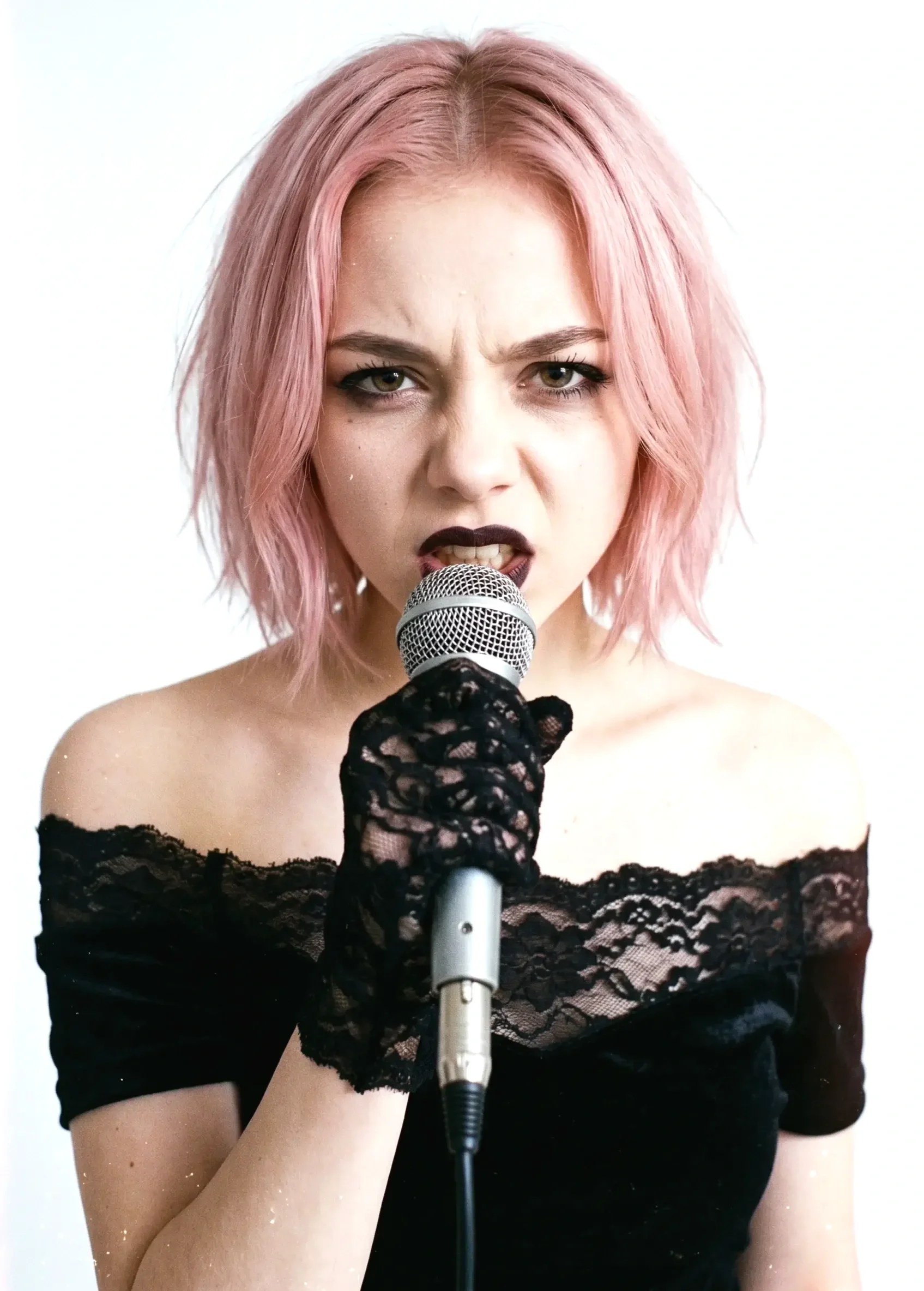 Rosa Thorn, lead singer of the female metal band Pink Paradox, sing in a microphone, wearing a black lace off-the-shoulder top and black lace glove, with an intense expression.