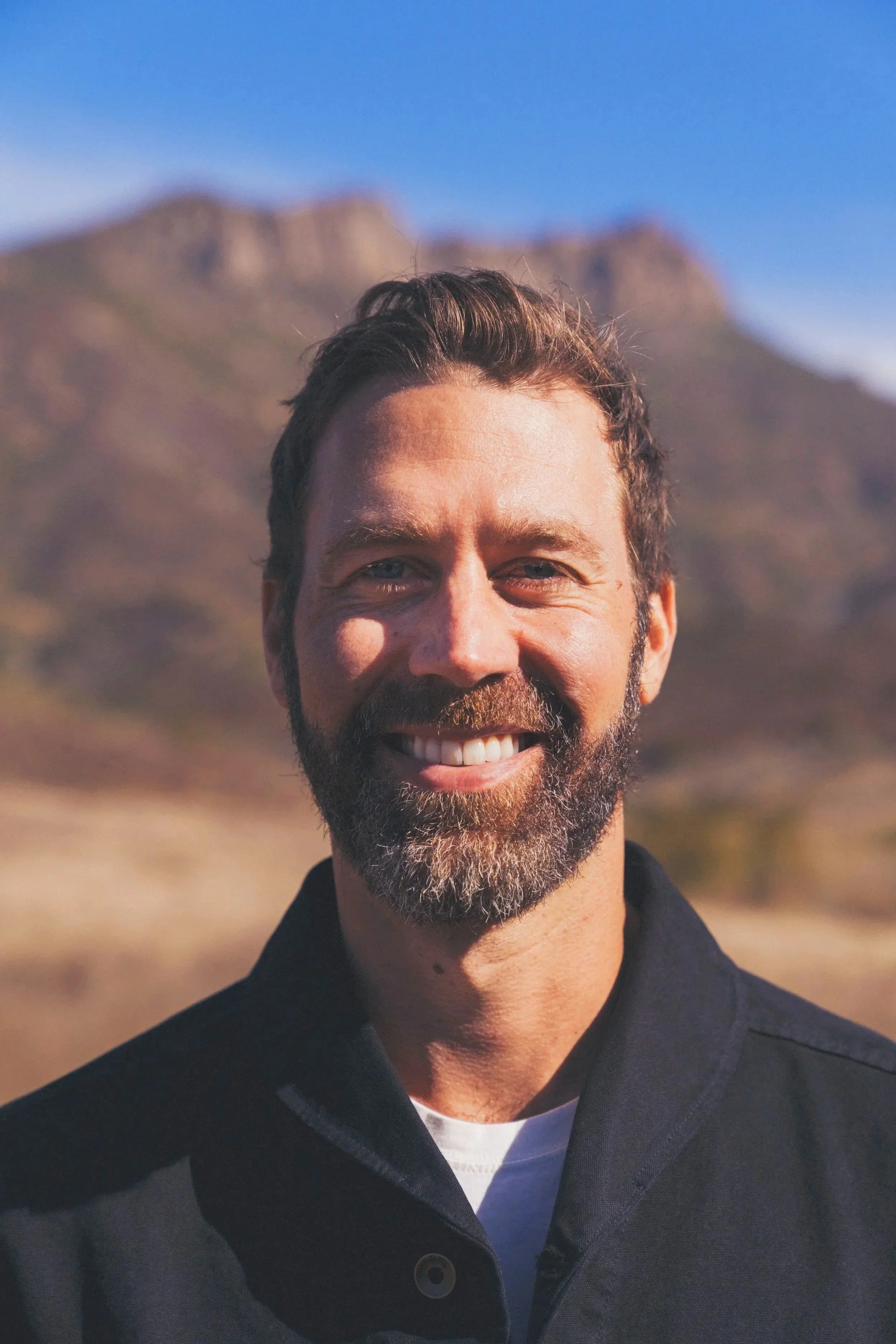 A campfire with flames rising against a dark, wooded background at night.