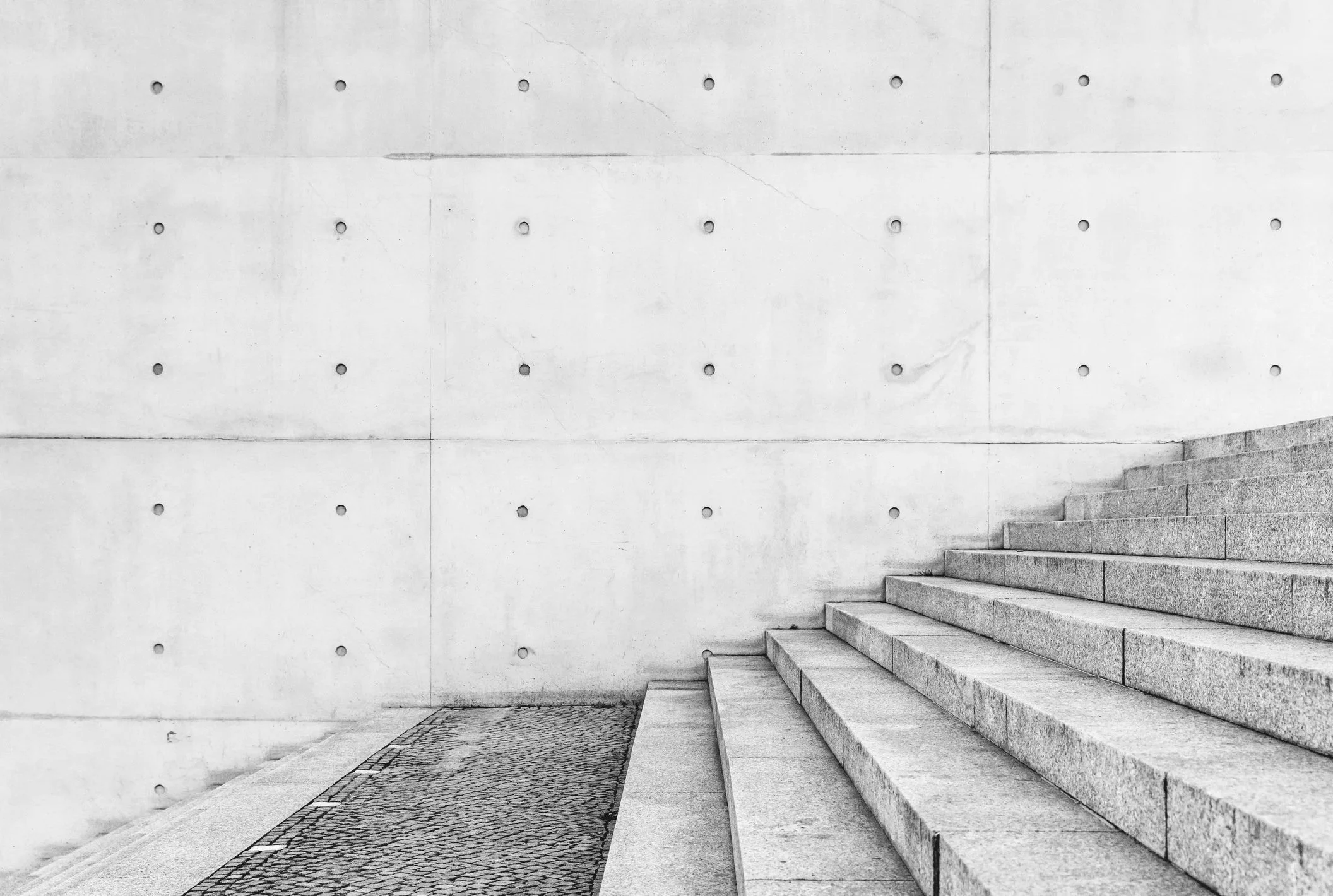 Concrete stairs next to a plain concrete wall with small round indentations.