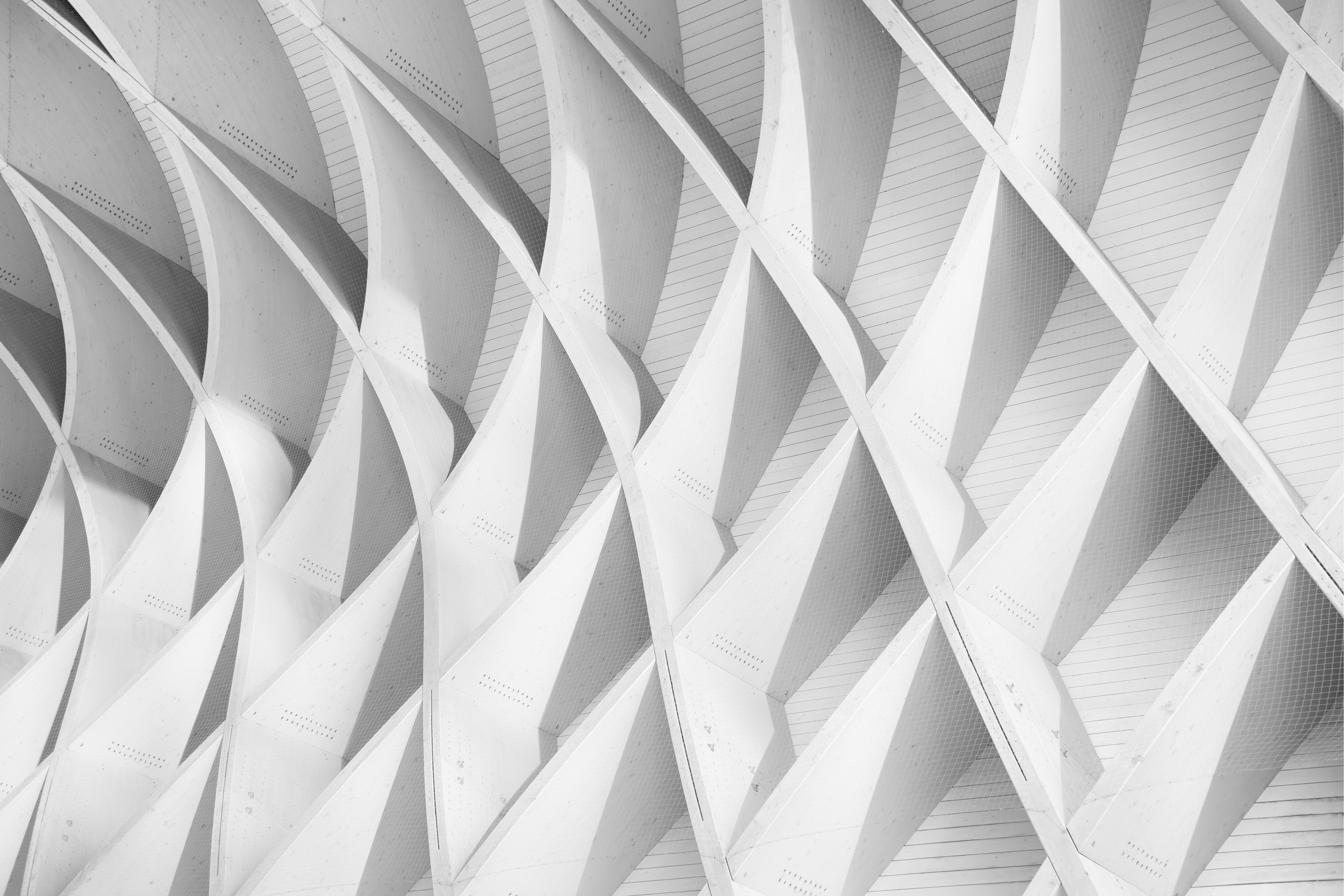 Close-up of a modern architectural building facade with repetitive, curved, white structural elements.