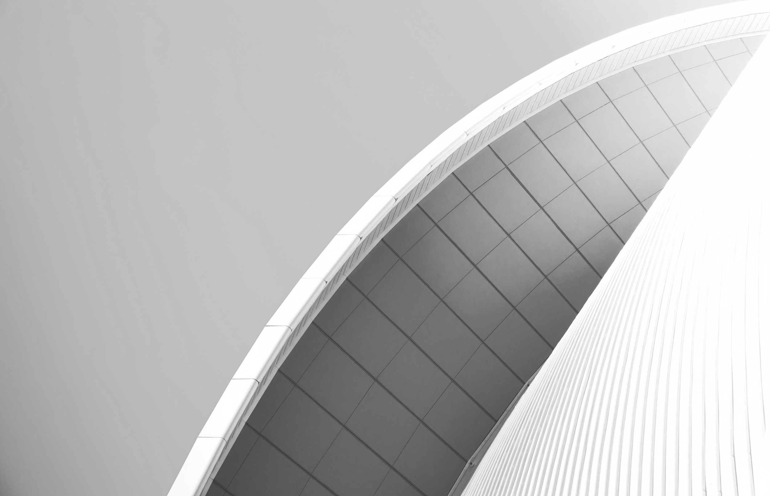 Close-up of a modern building with curved architecture, featuring smooth white exterior and large reflective glass windows.