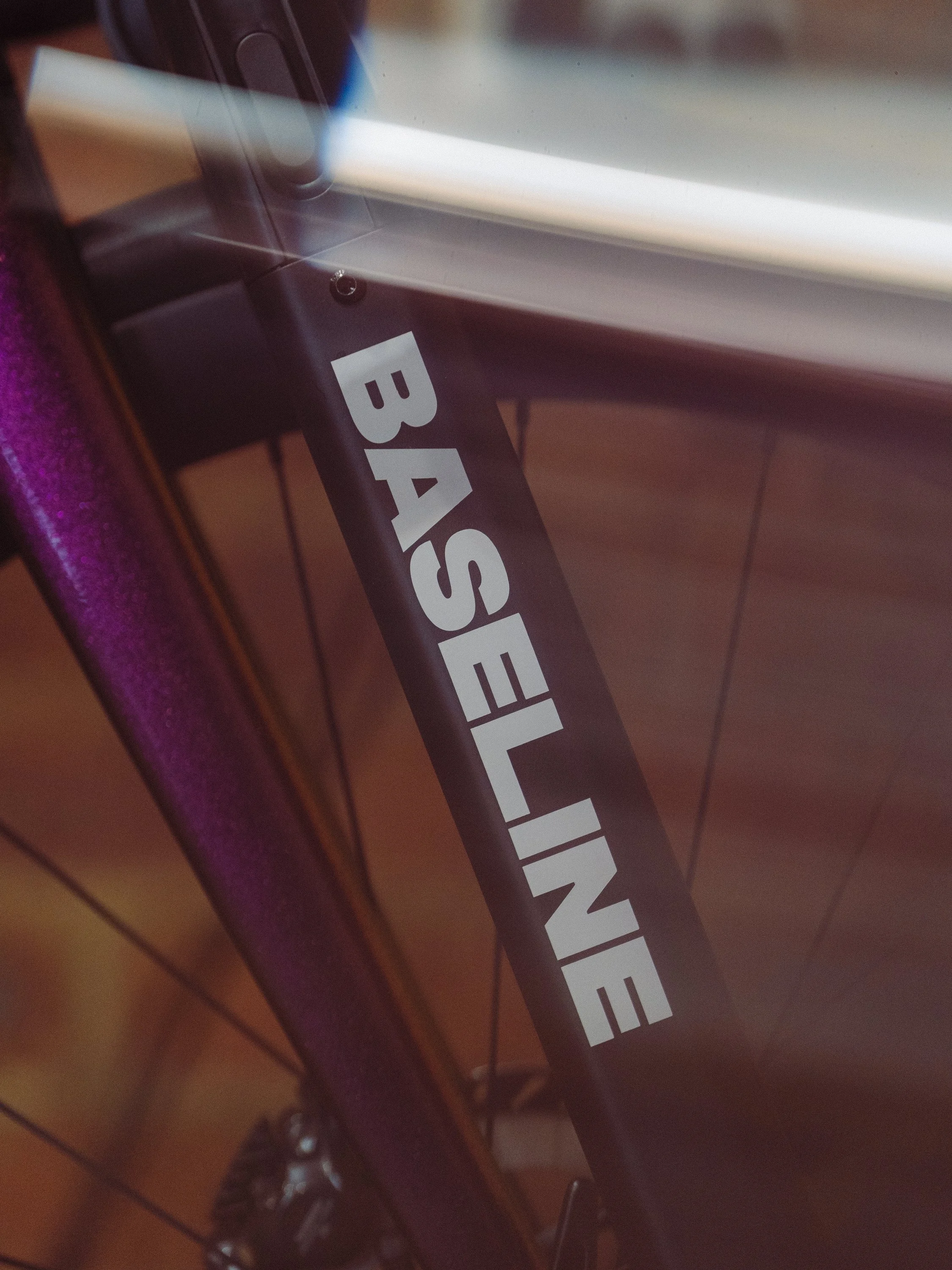 Close-up of a bicycle frame with a sticker that says 'BASSELINE' in white letters on a black background.