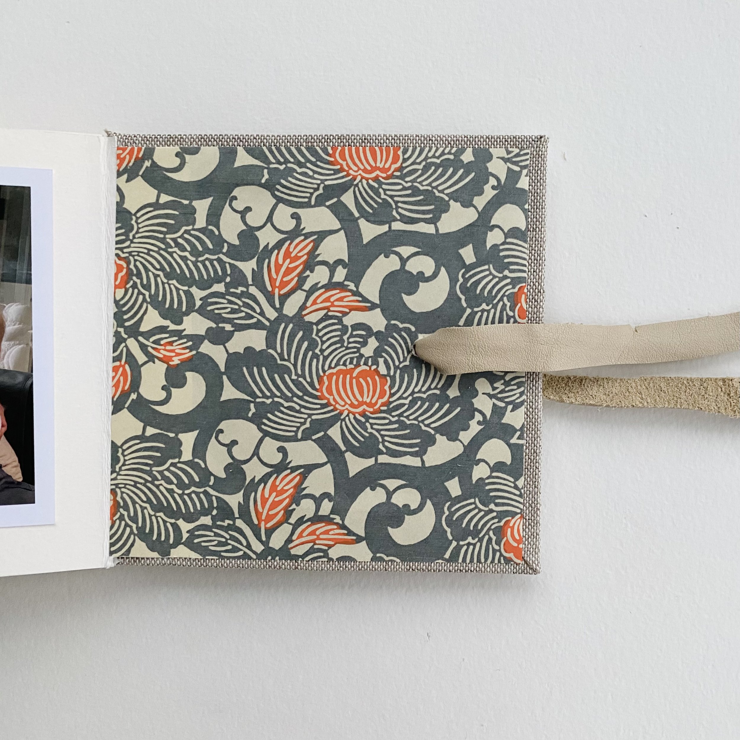Photo book covered with tweed book cloth and secured with a leather “belt” and filled with photos of a summer family visit. 5” square accordion.