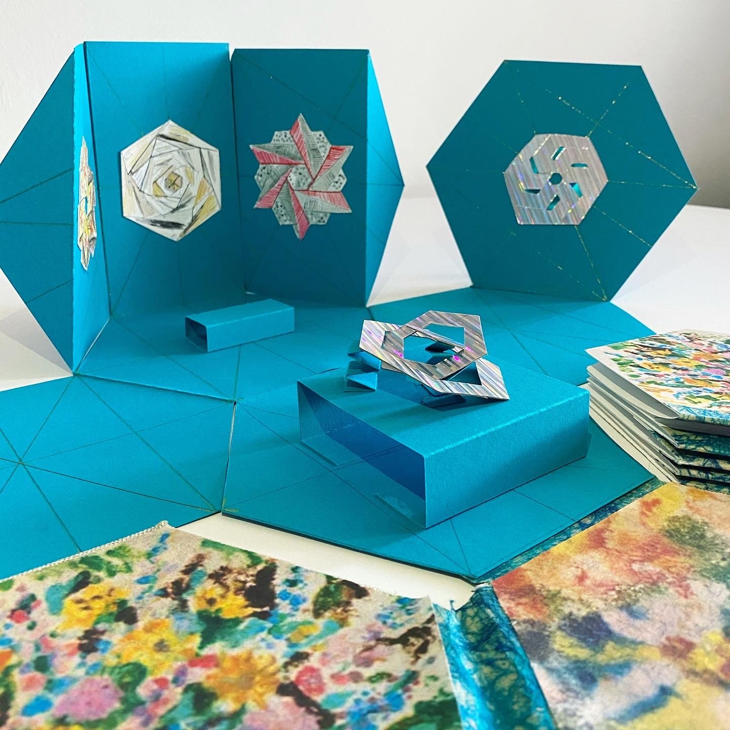This book is a pop-up Mini Monir Museum, featuring tiny illustrations of mirrored sculptures created by Monir Shahroudy Farmanfarmaian.