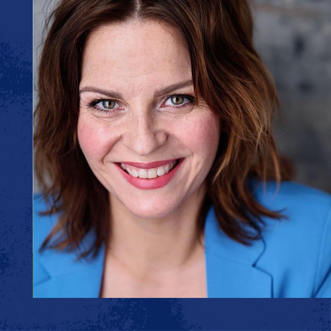 A smiling white woman with medium length brown hair wearing a bright blue blazer.