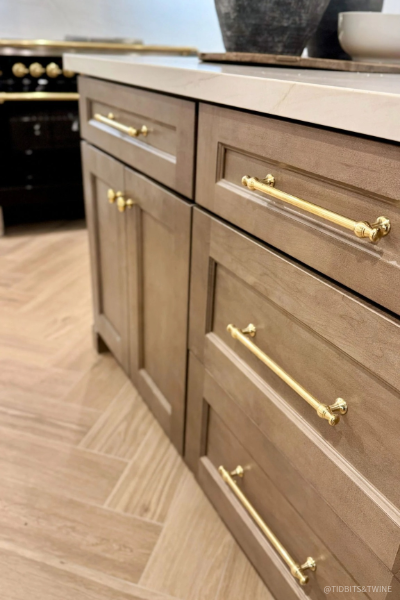 Close-up of walnut kitchen cabinets with brass drawer pulls, shaker-style doors, and natural wood grain, showcasing the warmth and craftsmanship of walnut cabinetry in modern kitchen design.