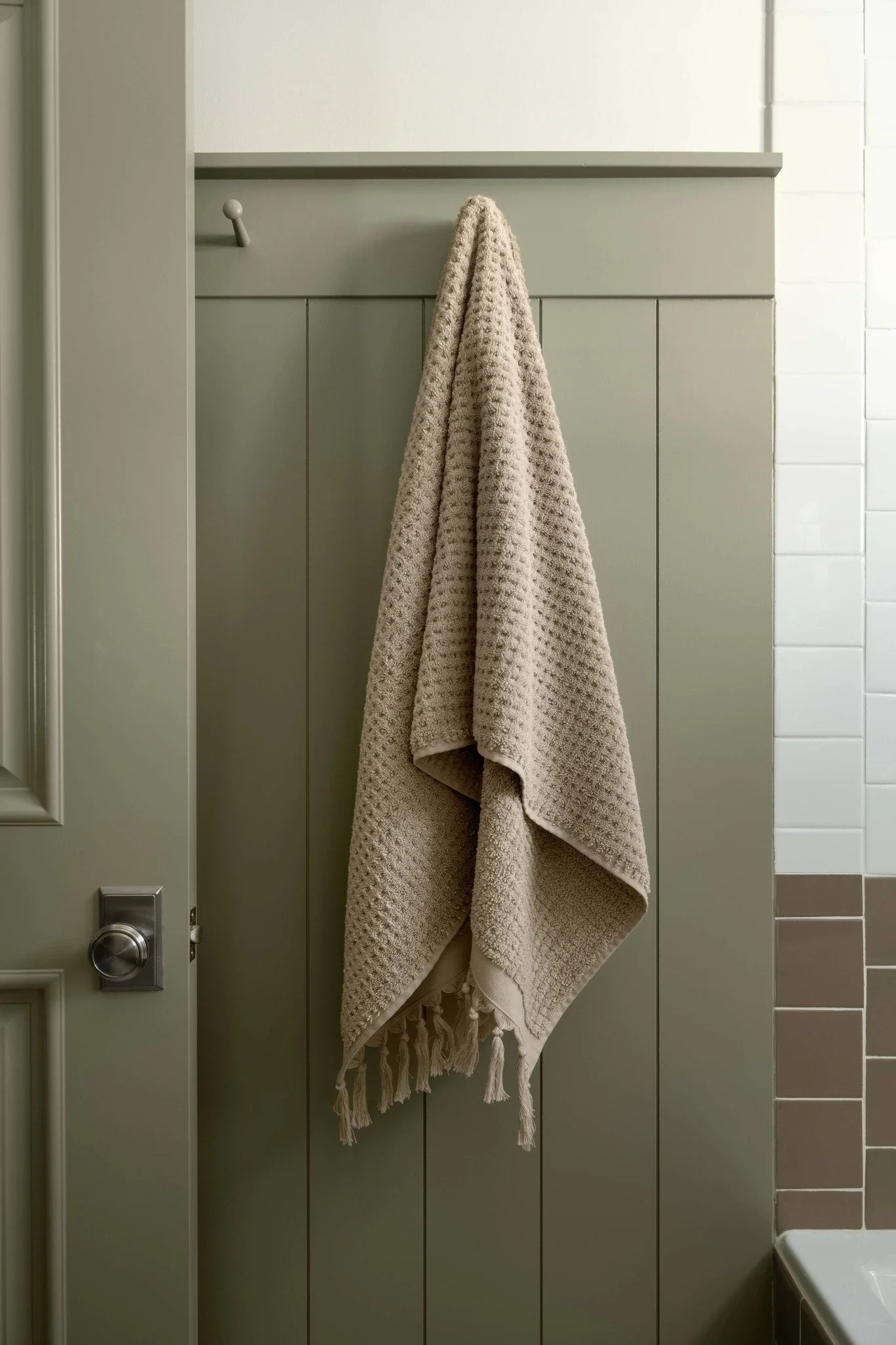 Sometimes the smallest details set the tone for the whole space. It begins with a simple board-and-batten wall, soft in sage, carrying texture and depth into the room. From there, cabinetry, tile, and trim all follow suit. Each layer adding character