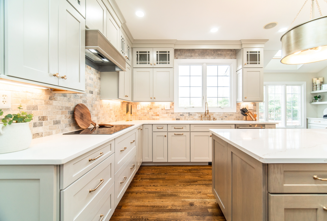 Soft neutral kitchen with white shaker cabinets, warm stone backsplash, and gold hardware creating a layered 2026 kitchen design