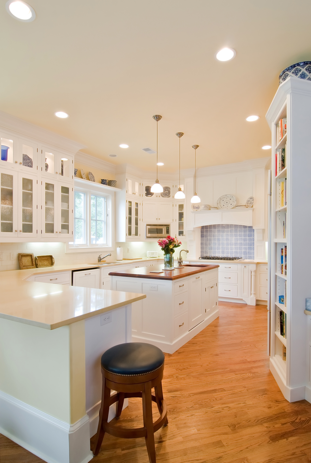 Bright white transitional kitchen remodel with large island and pendant lighting, ideal for homeowners deciding between remodeling or moving