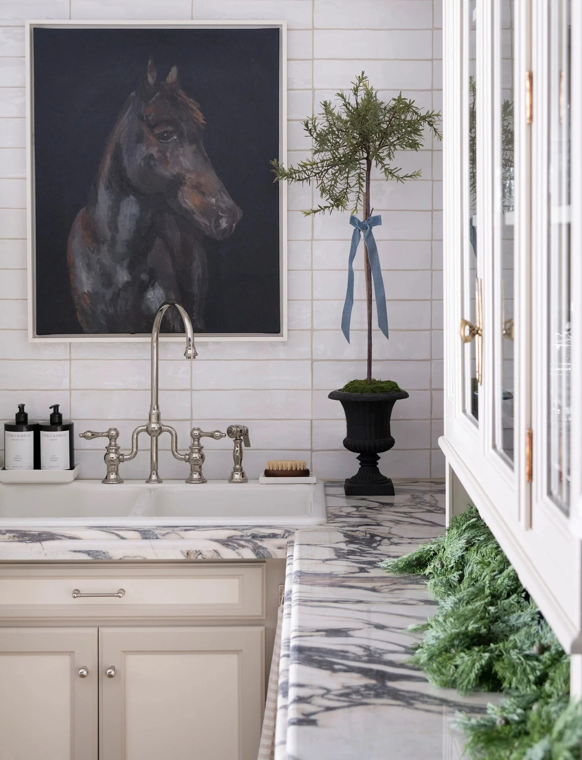 Custom cabinetry with marble countertops and integrated sink, styled with holiday greenery and classic details, showcasing timeless storage and craftsmanship in a refined home interior.