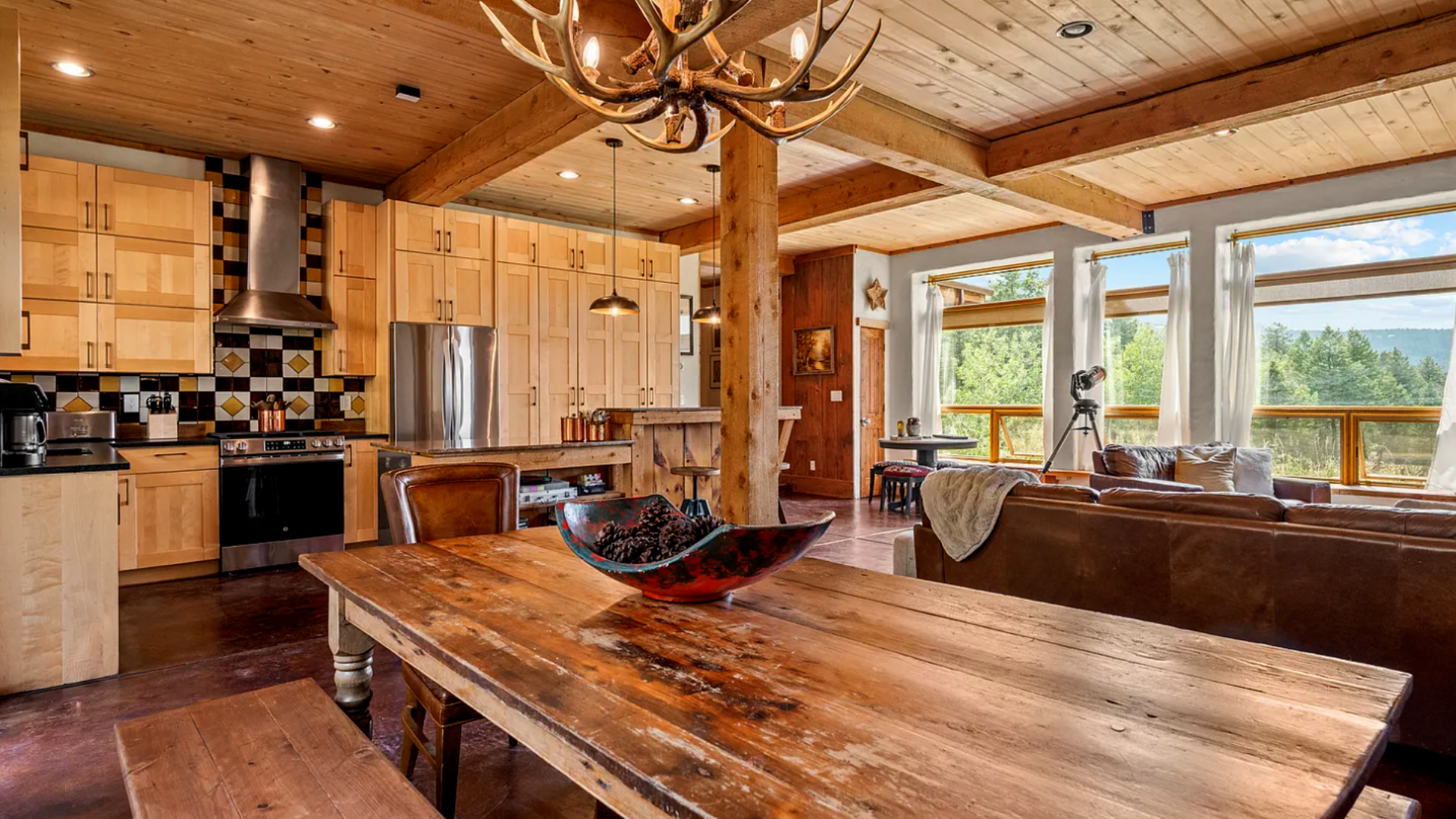 Rustic kitchen and dining room with knotty wood cabinets, exposed beams, and a large solid-wood table.