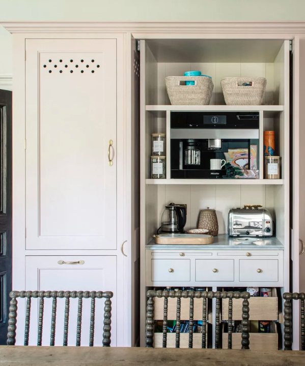 Elegant gray custom cabinetry with bi-fold appliance garage doors concealing a coffee machine, microwave, and toaster for a seamless luxury kitchen storage solution.