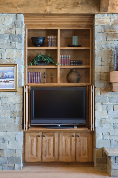 Custom wood entertainment center surrounded by natural stone, showcasing warm cabinetry, handcrafted millwork, and timeless home design elements that create lasting character.