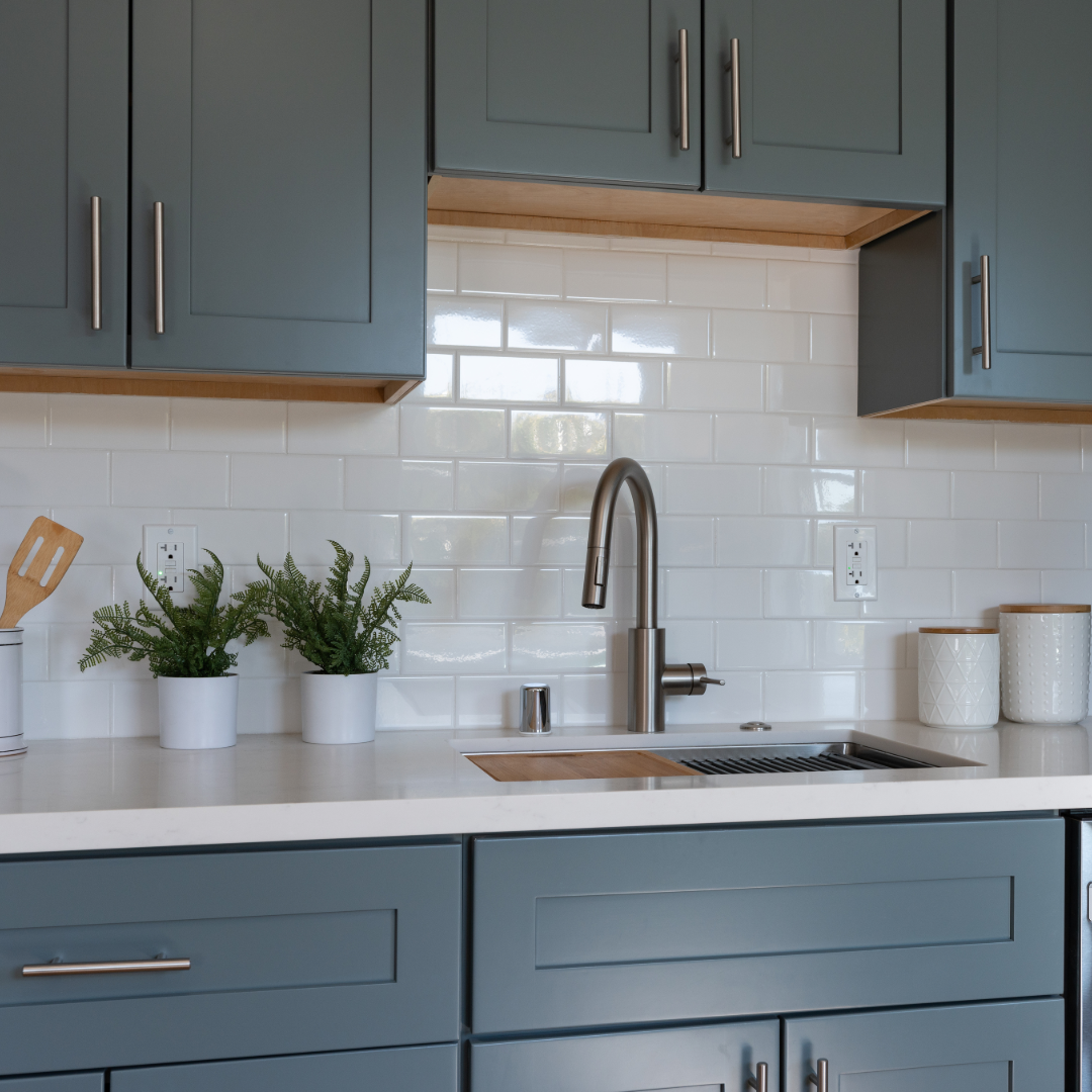 Blue-gray modern kitchen cabinets with brass hardware and white subway tile backsplash, representing a modernized kitchen remodel in 2026