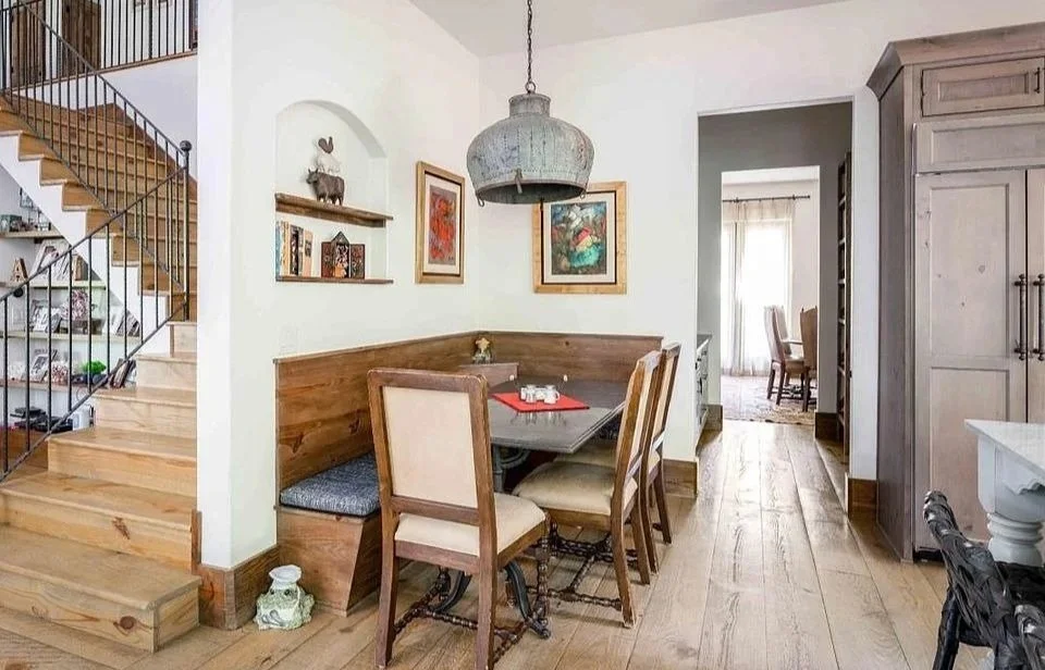 Dining nook beside a staircase with a wood banquette, round table, pendant light, and nearby cabinetry.