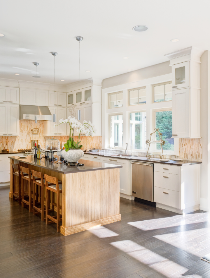 Custom kitchen with white cabinetry, natural wood island, marble countertops, and brass hardware adding warmth and contrast
