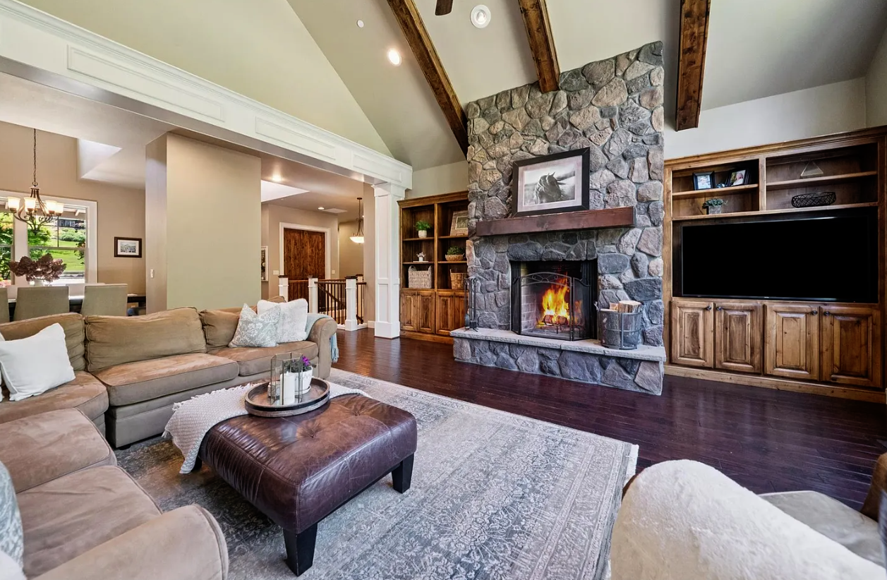 Living room with a floor-to-ceiling stone fireplace, television, and symmetrical wood built-in cabinets.
