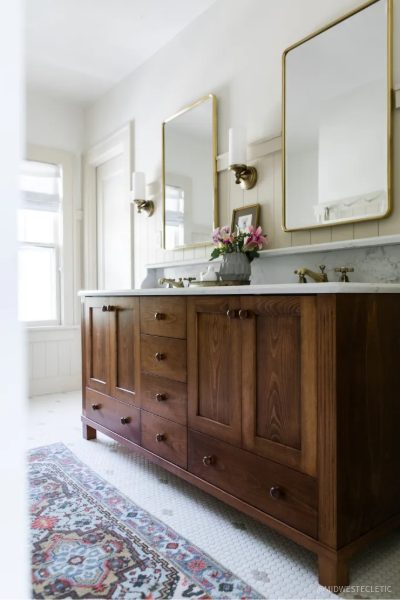 Custom walnut bathroom vanity with marble countertops, brass-framed mirrors, and warm wood cabinetry, demonstrating how walnut adds timeless beauty and character to bathroom design.