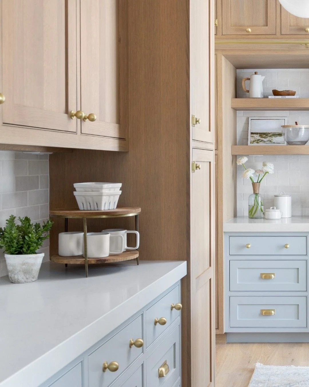 Light wood kitchen cabinetry paired with soft blue base cabinets, brass hardware, open shelving, and white quartz countertops in a timeless 2026 kitchen design by Hester Family Millwork in Gainesville, Georgia.