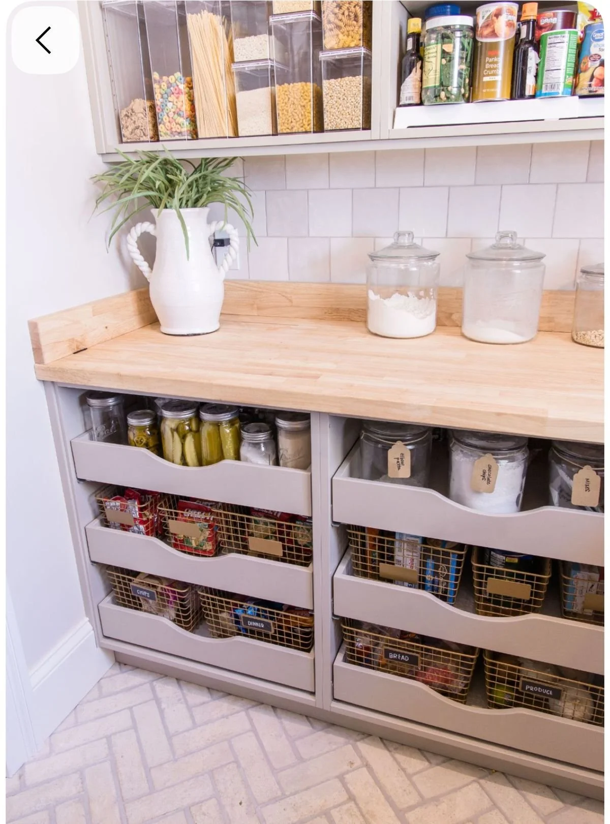 Custom kitchen pantry with wood countertop, deep pull out drawers, and labeled basket storage, showing organized dry goods and everyday pantry items in a functional cabinetry layout.