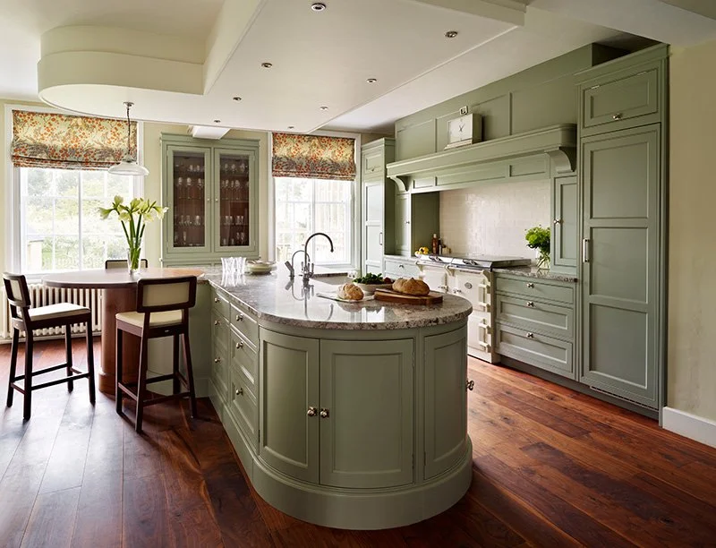 Curved kitchen cabinetry with painted millwork, detailed paneling, and a rounded island, showcasing classic craftsmanship and furniture-inspired cabinet design by Davonport.