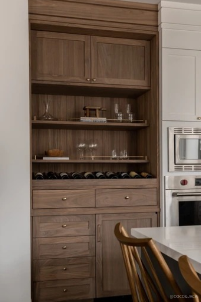 Custom walnut cabinetry beverage station featuring open shelving, integrated wine storage, brass hardware, and warm wood grain details that add timeless character and functional storage to a luxury kitchen design.