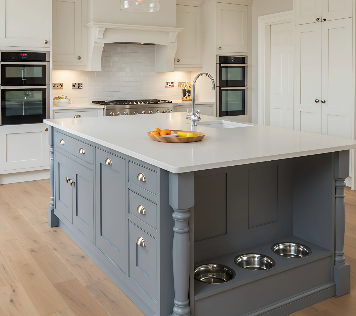 Custom kitchen island in soft gray with white quartz countertop and built-in pet feeding station, designed by Hester Family Millwork for style and function.
