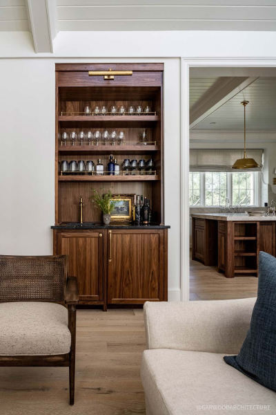 Custom walnut built-in cabinet and bar area with open shelving, brass accents, and integrated storage, creating a sophisticated transition between the living room and kitchen.