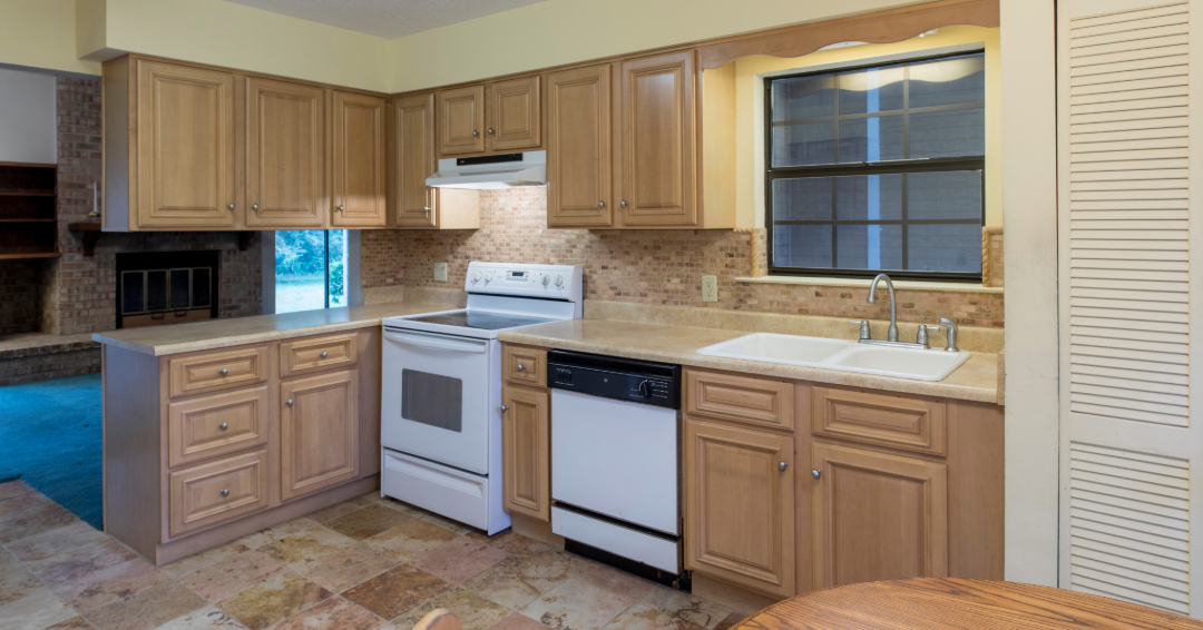 Outdated builder grade kitchen cabinets with wood raised-panel doors, standard appliance layout, and limited storage, shown before a cabinet replacement or kitchen remodel by Hester Family Millwork in Georgia.
