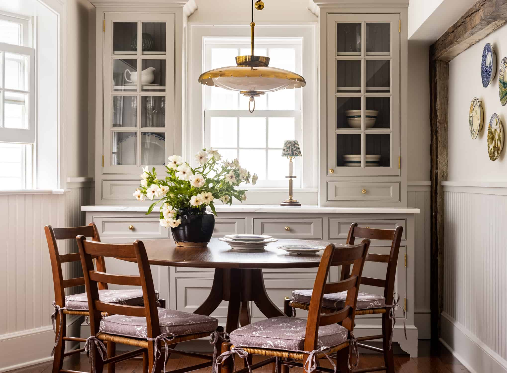 Custom dining room built-in cabinetry with glass-front upper cabinets, warm wood dining furniture, and decorative details that add personality and character to the home.