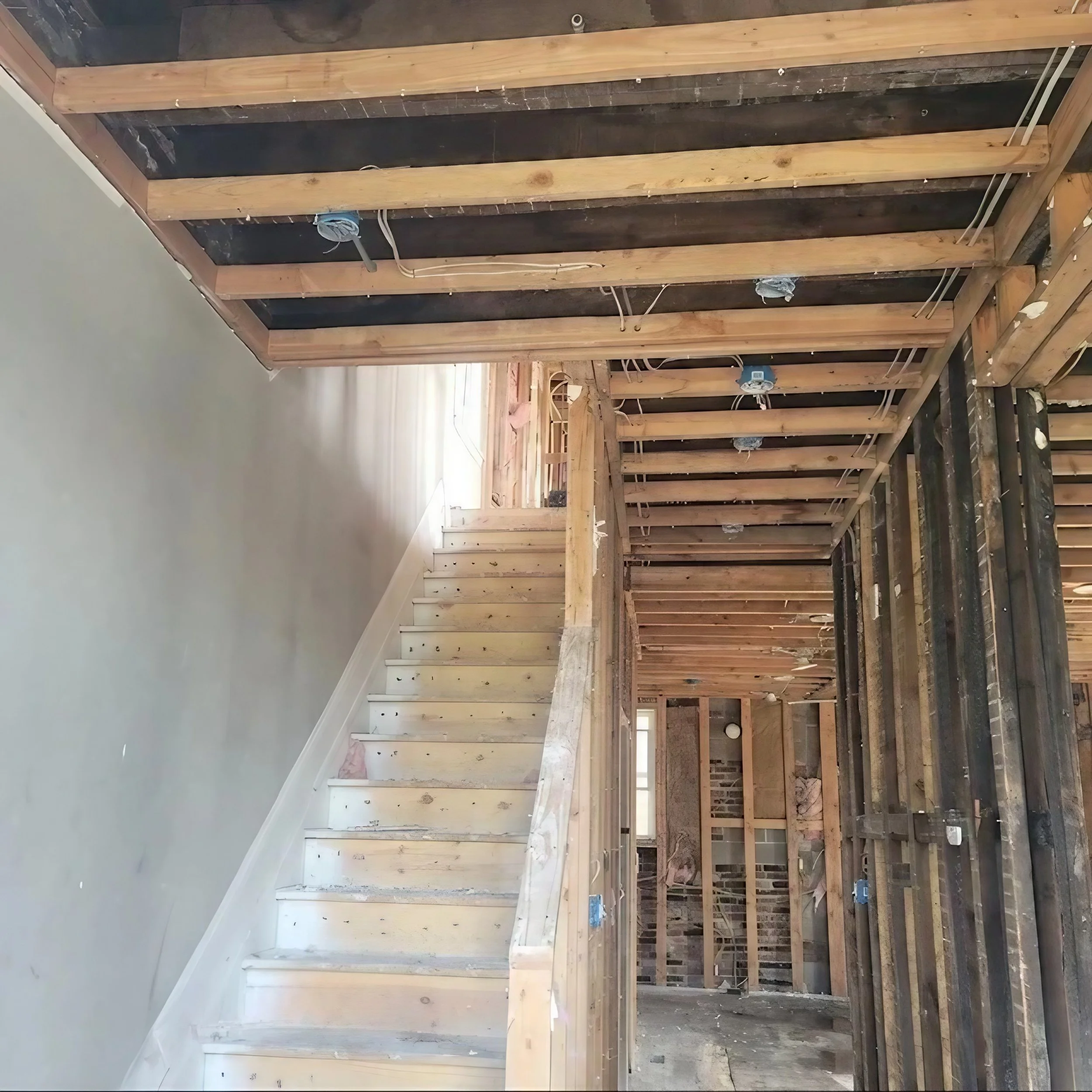 Construction site with wooden framing and stairs, unfinished interior walls.