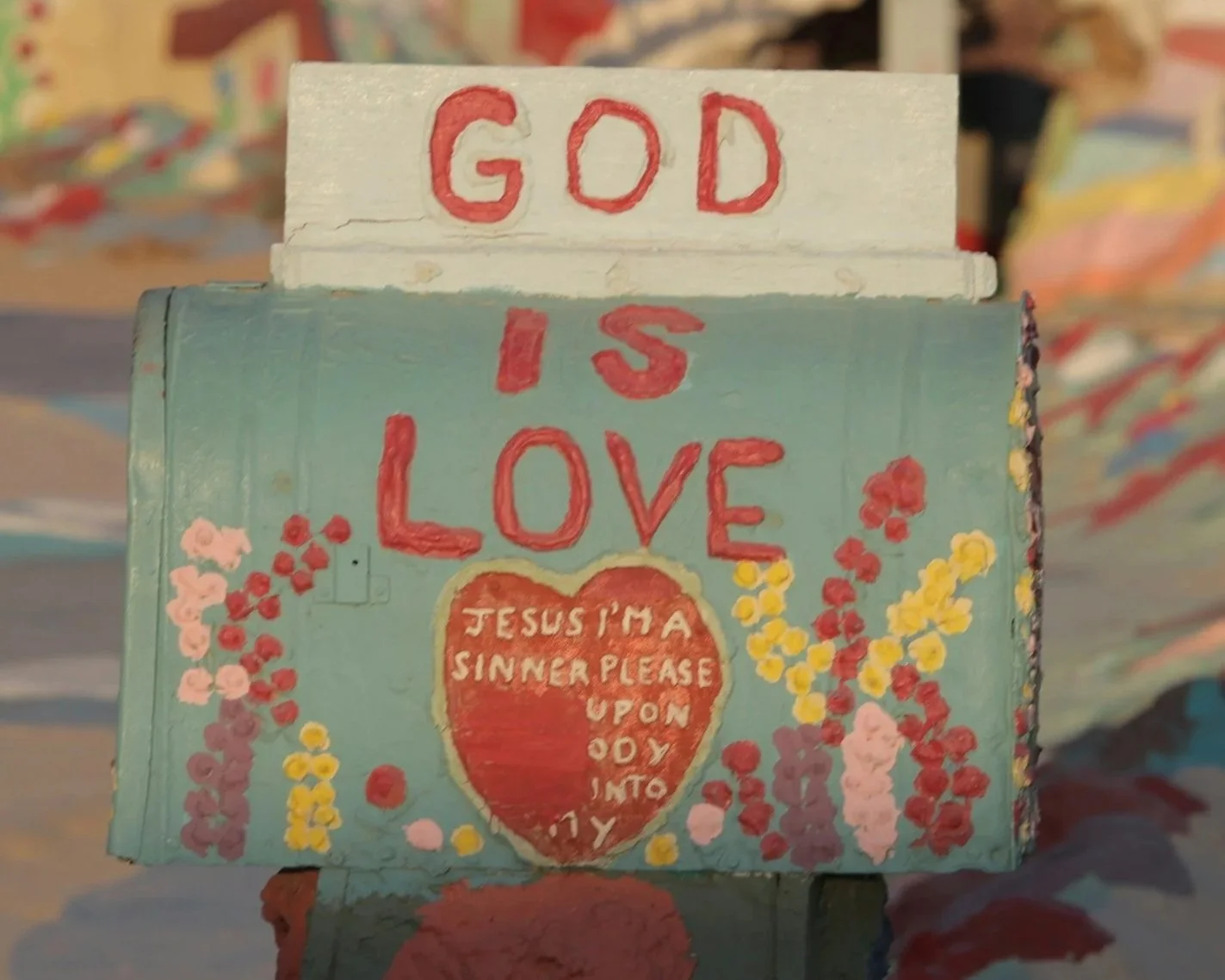 Colorful sign with the words 'God is Love' and a heart shape containing a prayer message.