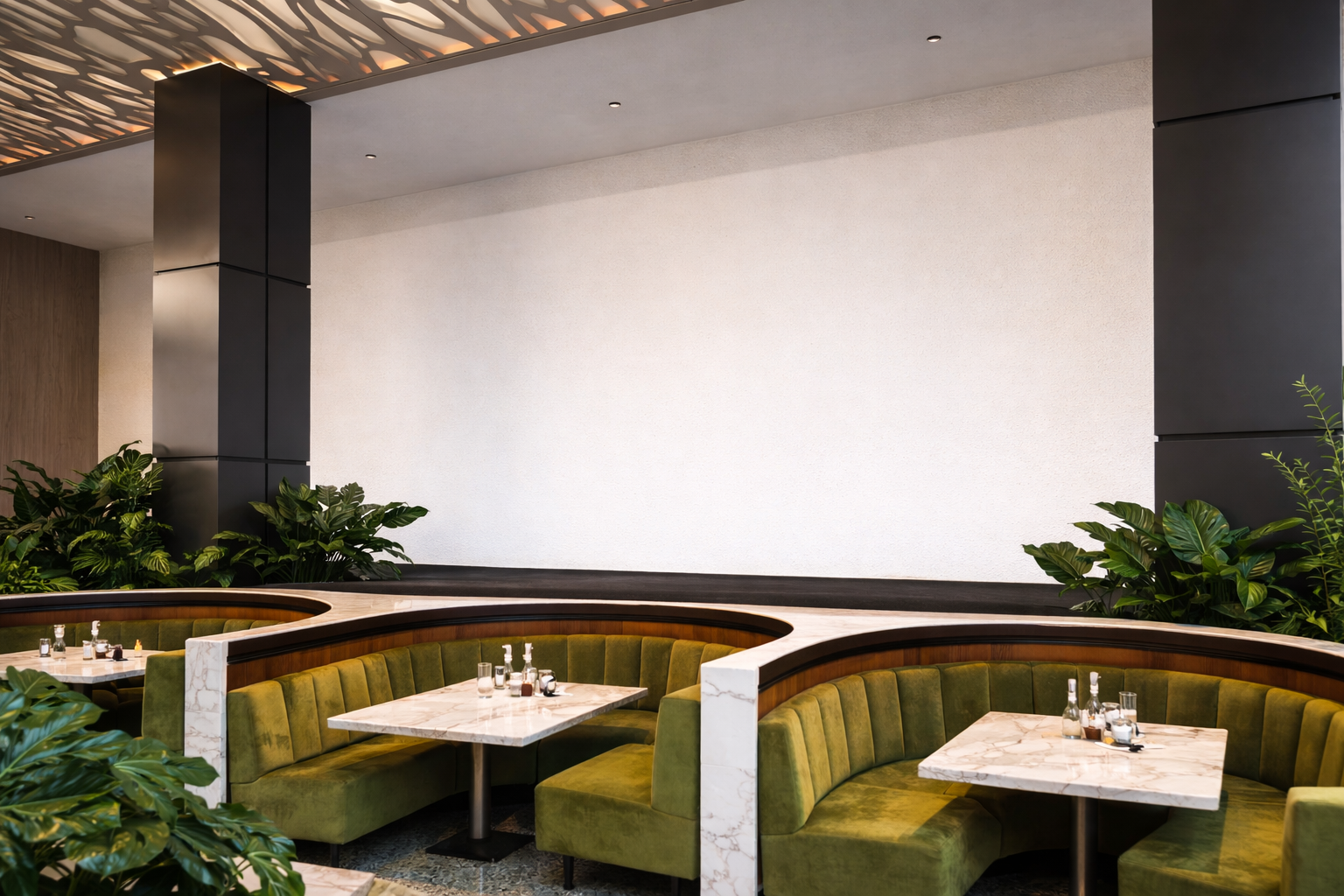 Restaurant booth seating with green velvet upholstery, marble-topped tables, and surrounding greenery in a modern setting.