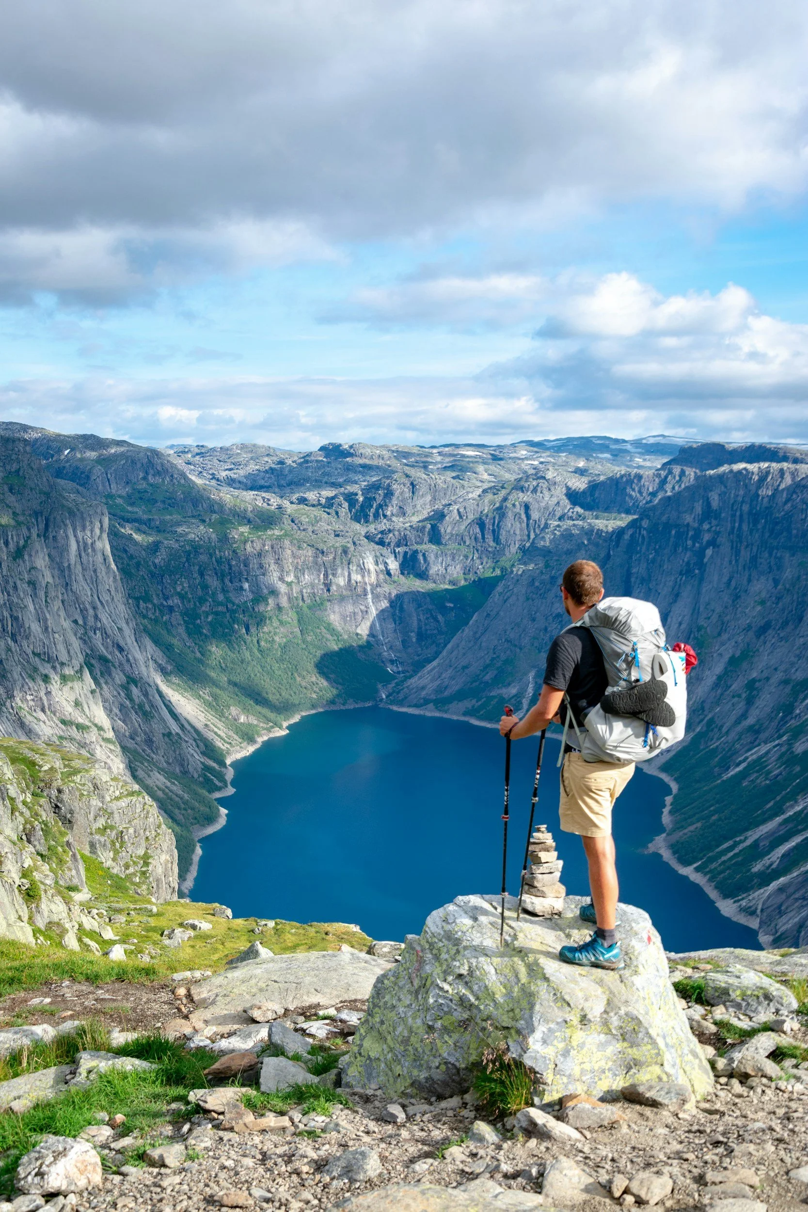 Hiker standing on a mountain overlook above a lake and rocky peaks