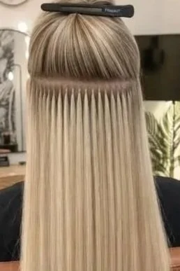 A person getting a hair treatment with straight, blonde hair sectioned and combed through a hair styling tool.