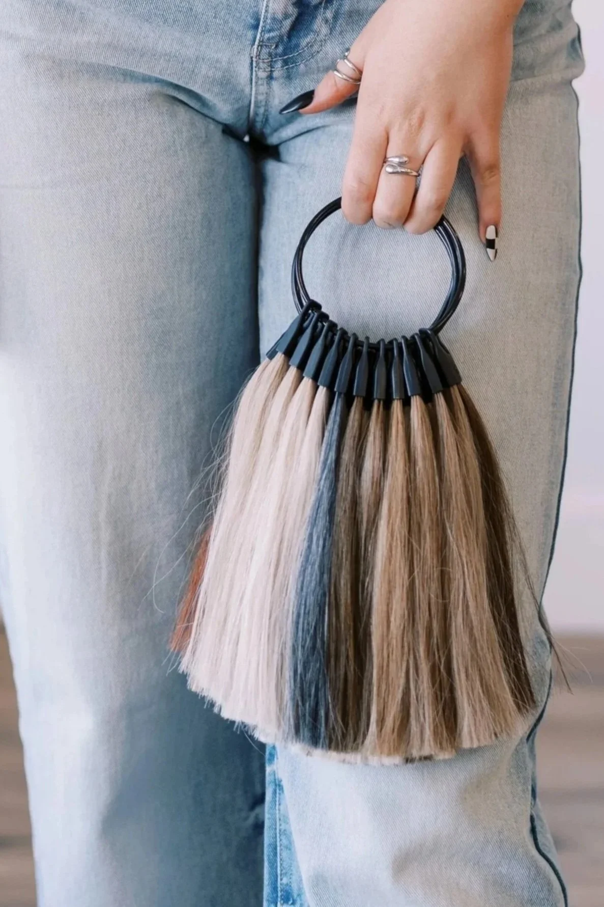 Person holding a color swatch fan with hair color samples against denim jeans