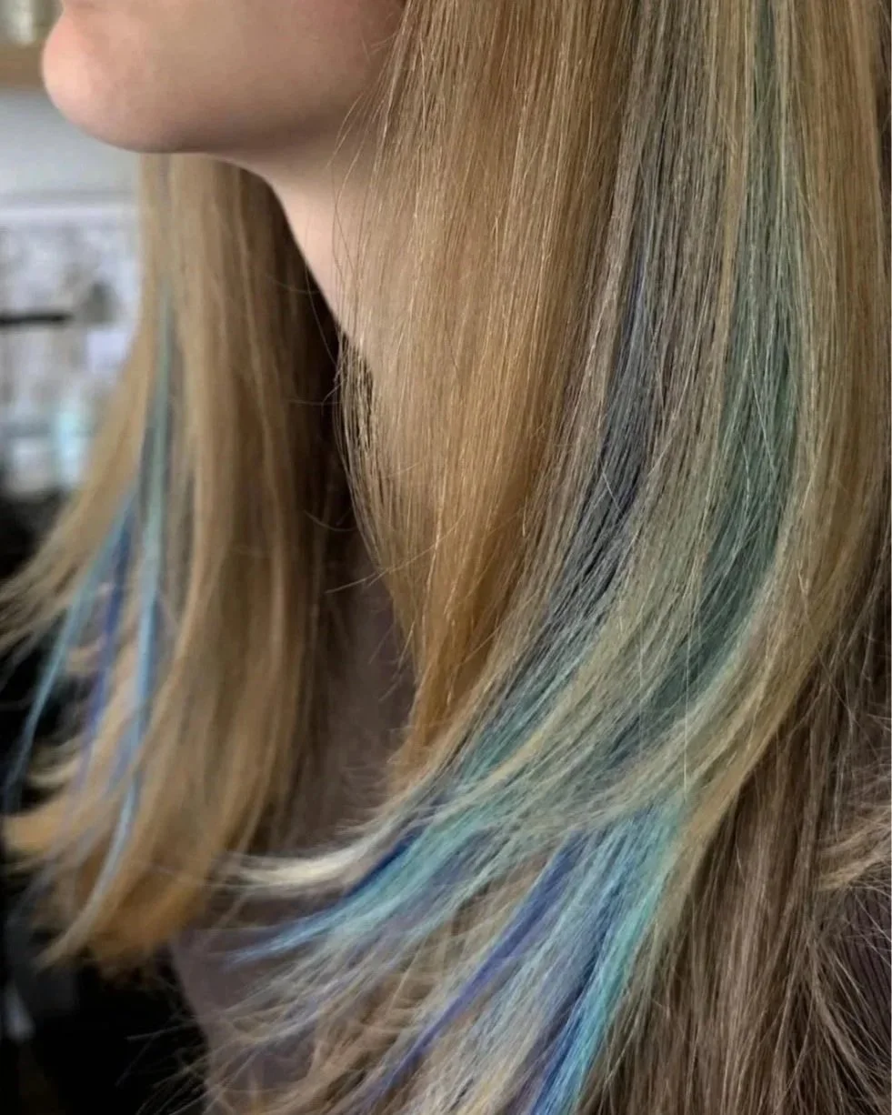 Close-up of a woman's blonde hair with streaks of blue and green.