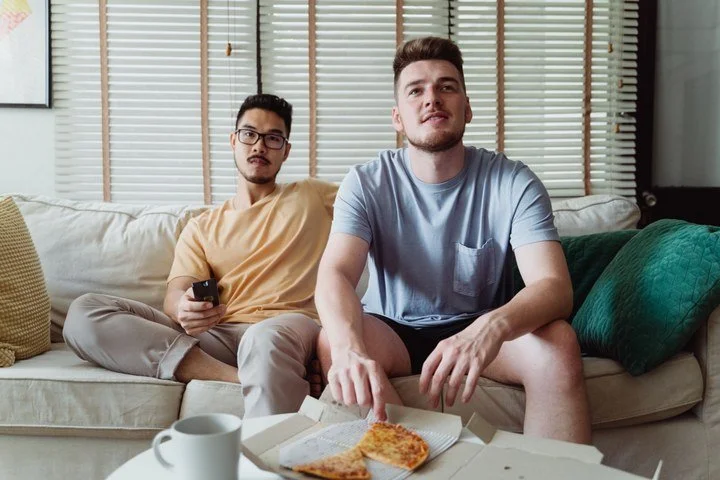Two partners sitting together on a couch while appearing emotionally disconnected, illustrating feeling like roommates, emotional distance, and relationship counseling.