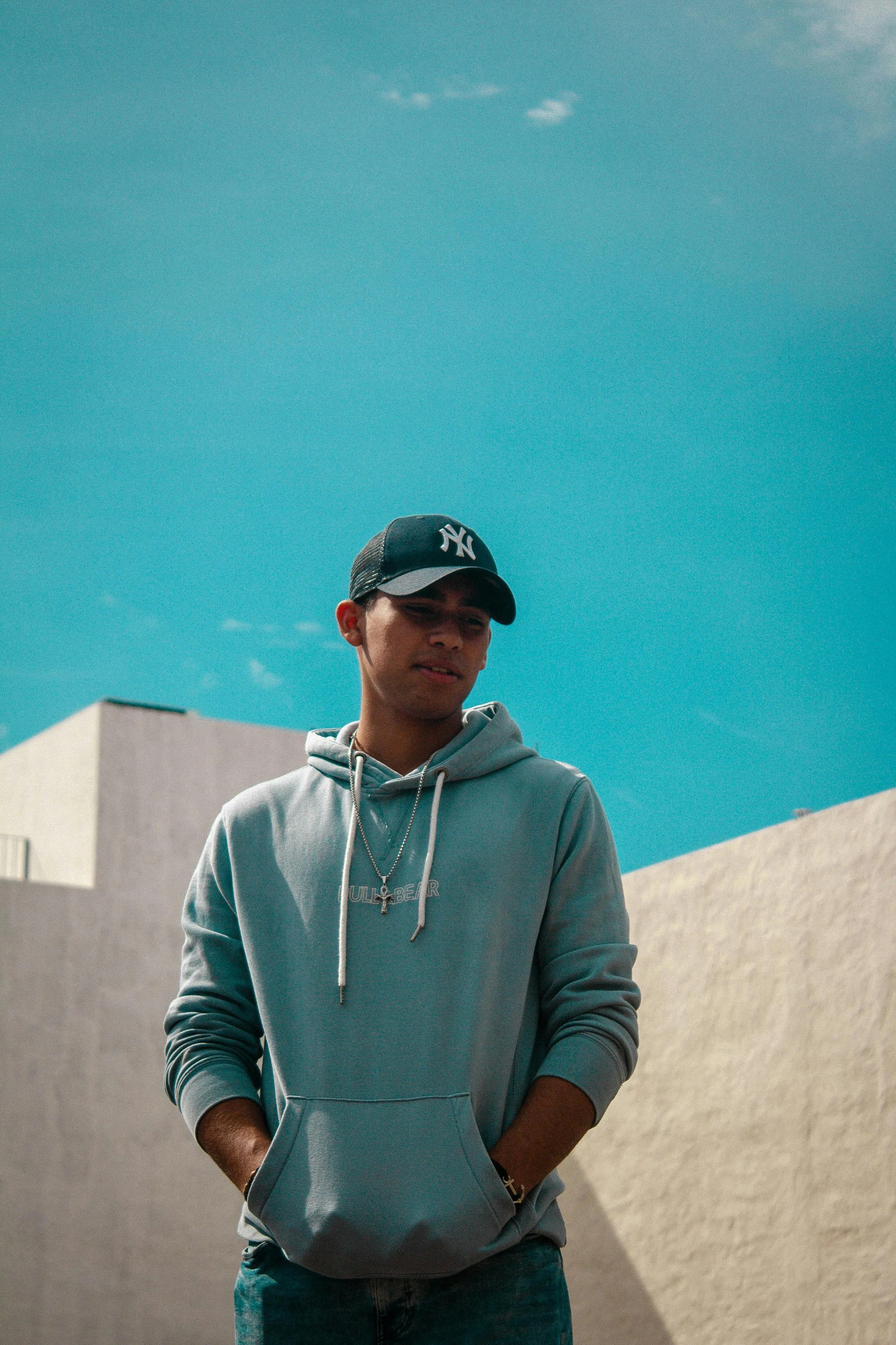 A person standing alone under a bright sky with hands in pockets, symbolizing the pause and reflection needed to examine the mental health impact of hustle culture.