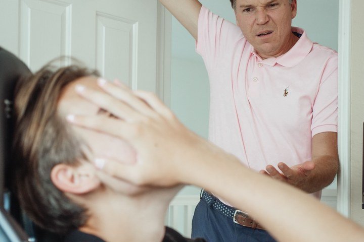 Young adult feeling frustrated during a tense conversation with a parent, illustrating family dynamics, boundaries, and therapy for young adults.