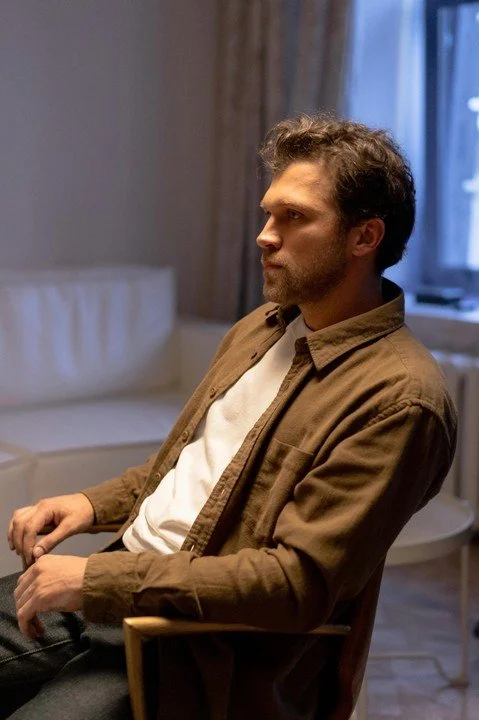 Man sitting alone in a dimly lit room, looking thoughtful and reflective, representing emotional introspection and patterns explored in therapy for men in San Francisco.