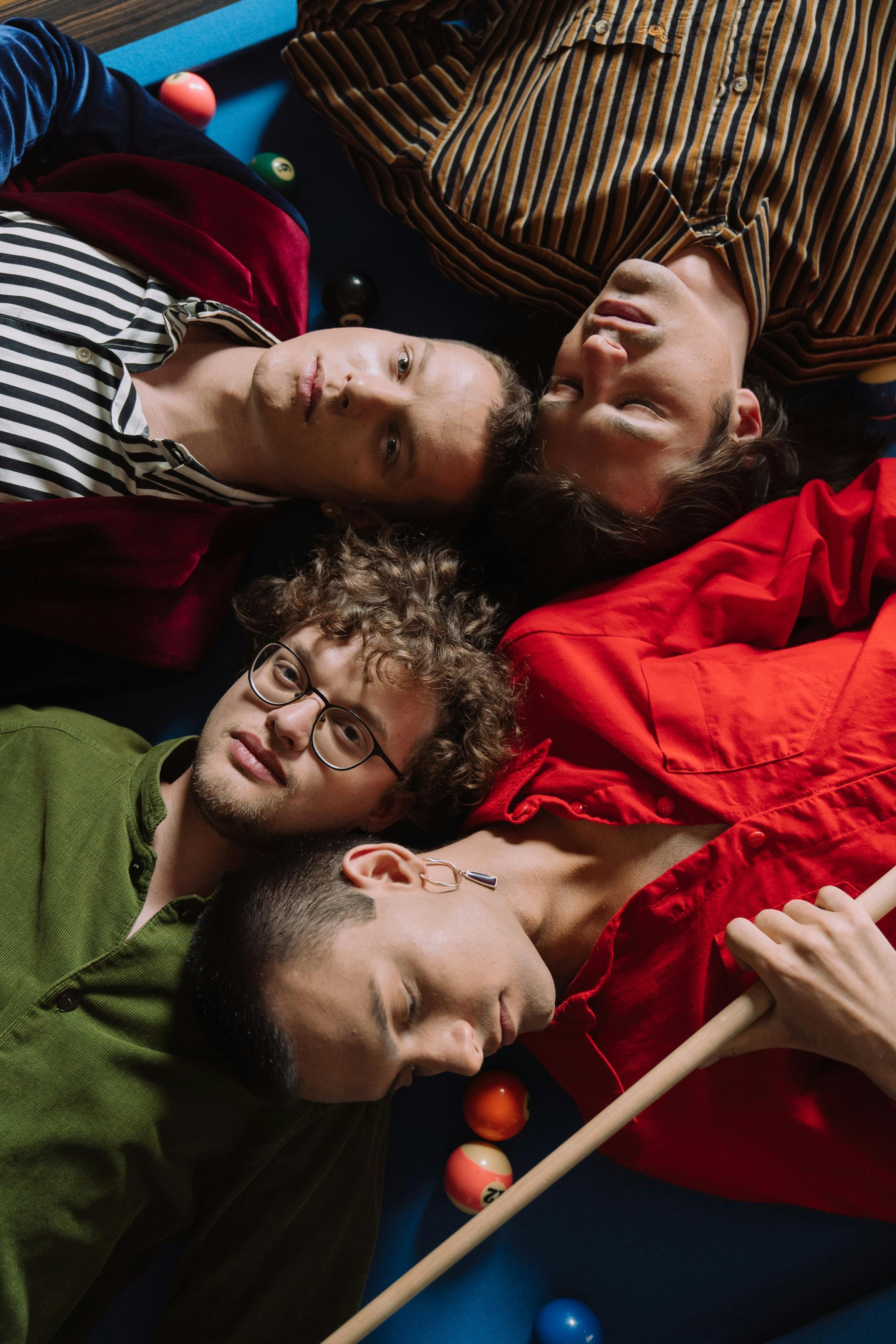 Group of queer adults lying together in a relaxed setting, representing connection, identity, and community explored in queer-affirming psychotherapy in San Francisco.