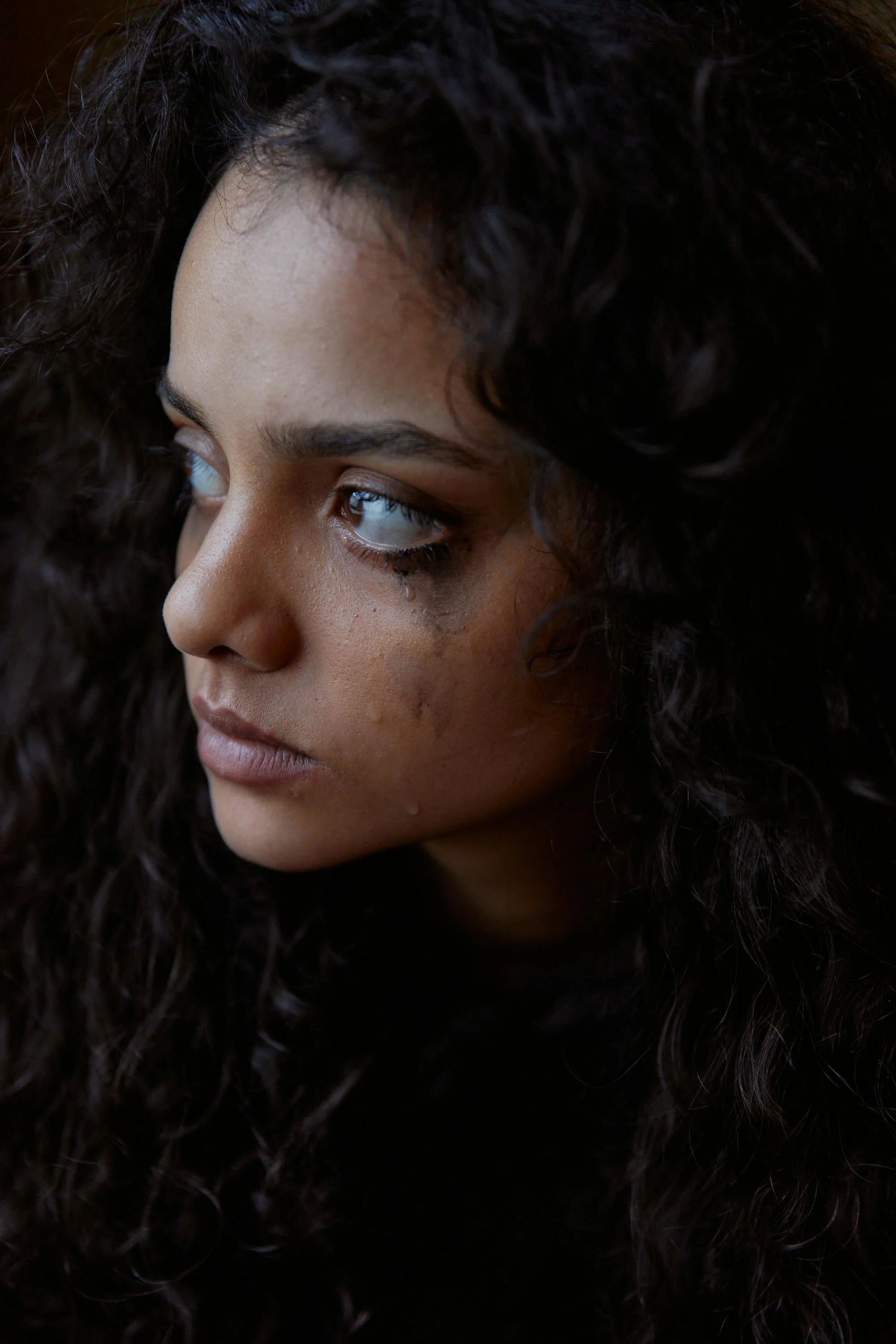 A person with tear-streaked makeup looking away in sorrow, symbolizing the deep emotional layers explored in psychodynamic therapy for complicated grief.