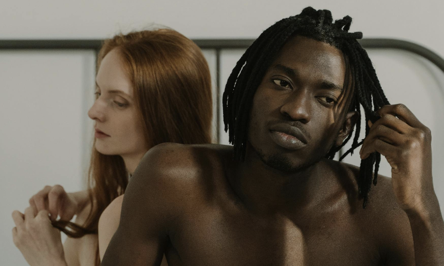 A man looking distant and uncomfortable while sitting beside a partner, symbolizing the emotional weight of sexual shame and its impact on self-worth.